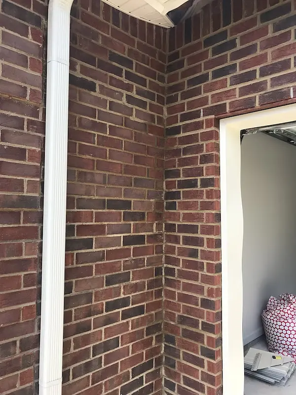 Close-up of restored brick near a downspout and garage opening
